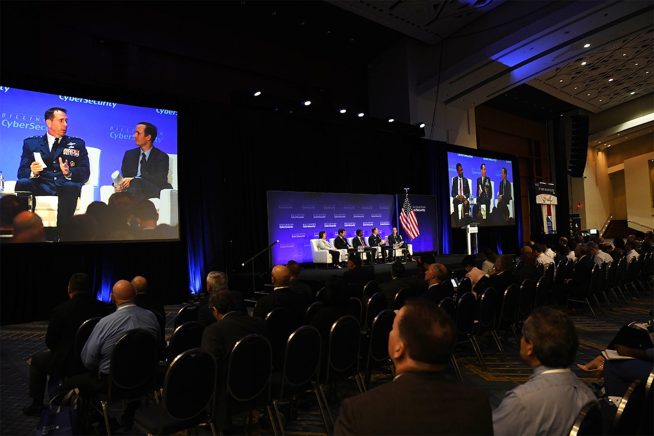 A man in a military uniform, who is on a five-person panel, speaks to an audience.