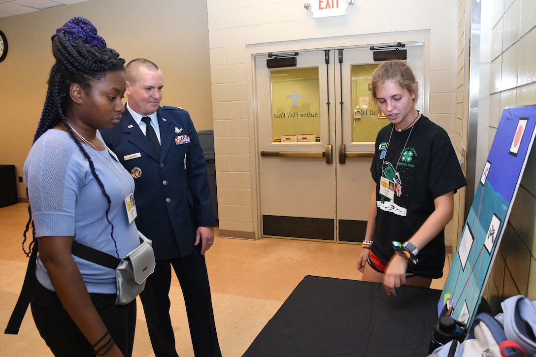 Maj. Benjamin Calhoon, 22nd Air Force executive officer, listens to presentation from Drew Cribbs, high school student from Madison, Ga., about GPS technology at Rock Eagle 4-H Center in Eatonton, Ga., Aug 17, 2019. Maj. Calhoon served as capnote speaker for the event and in previous assignments oversaw operations and policy for GPS.
