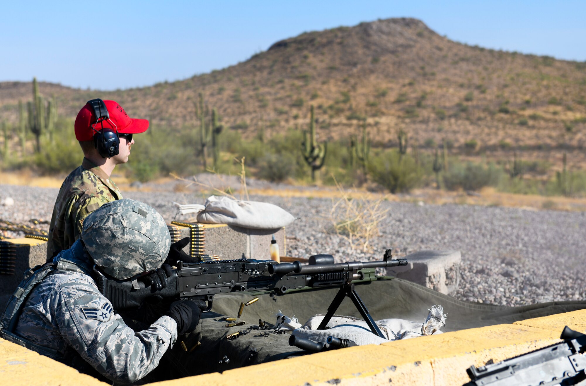 Staff Sgt. Casey Church, 56th Security Forces Squadron combat arms training and maintenance instructor, monitors Senior Airman Alexander Friend, 56th SFS law enforcement patrolman, while he fires a M240B machine gun Sept. 4, 2019, at the Arizona National Guard range in Florence, Ariz.