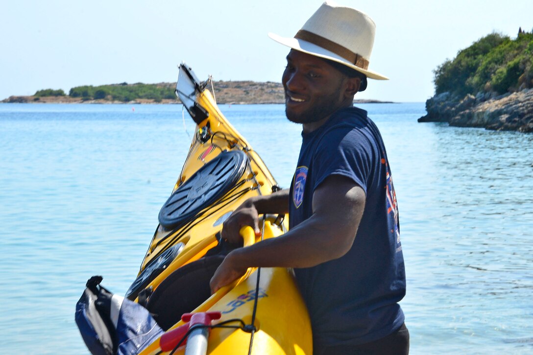 Man carries yellow kayak.