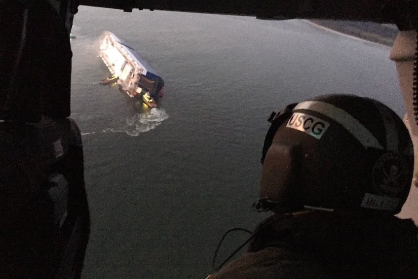 A large cargo ship lists on one side.