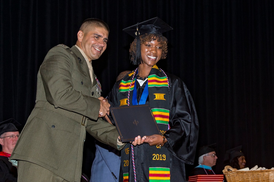 Chief Warrant Officer 3 Crystal Ledbetter, right, the legal administration officer with the Legal Services Support Section-West, Marine Corps Base Camp Pendleton, receives her diploma during the 2019 Base Education Center Commencement Ceremony at the Pendleton Base Theater and Training Center on Camp Pendleton, California, Sept. 6, 2019. The graduating class of 133 students earned 141 degrees from three of the colleges offered through the Base Education Center. (U.S. Marine Corps photo by Lance Cpl. Drake Nickels)