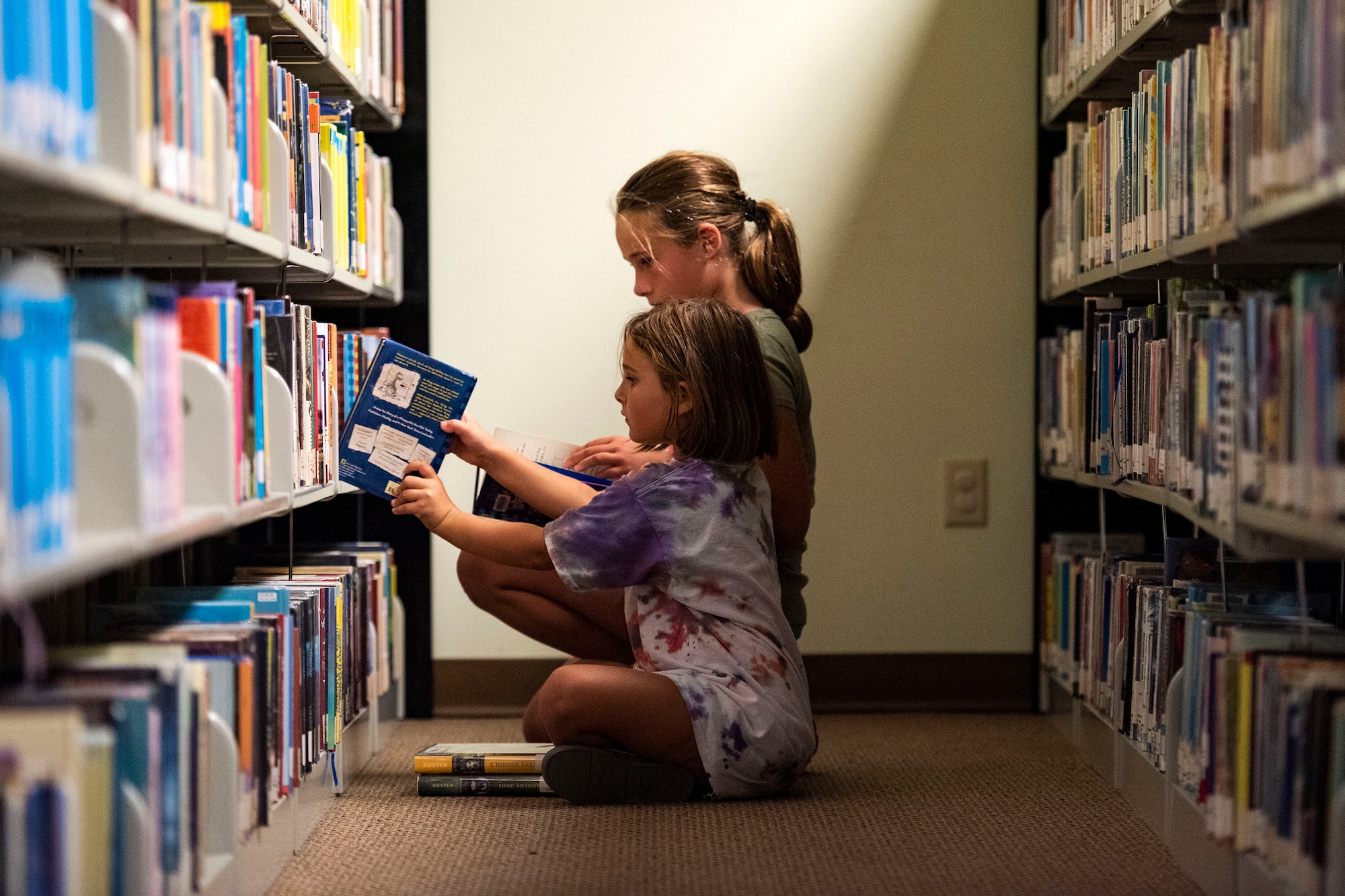 Zophia, front, and Athena, daughters of Lindsay Clark, military spouse, pick out a book Sept. 5, 2019, at Moody Air Force Base, Ga. The Information Learning Center provides a means of morale and serves as the central hub for all informational and educational growth for Airmen and families. (U.S. Air Force photo by Senior Airman Erick Requadt)