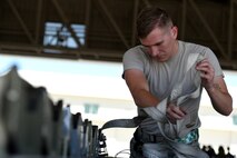 A 432nd Maintenance Group Airman removes the straps from a bomb at Creech Air Force Base, Nevada, July 19, 2019. Weapons Airmen represent their unit in these competitions that showcase their job knowledge and proficiency throughout the year. (U.S. Air Force photo by Airman 1st Class William Rio Rosado)
