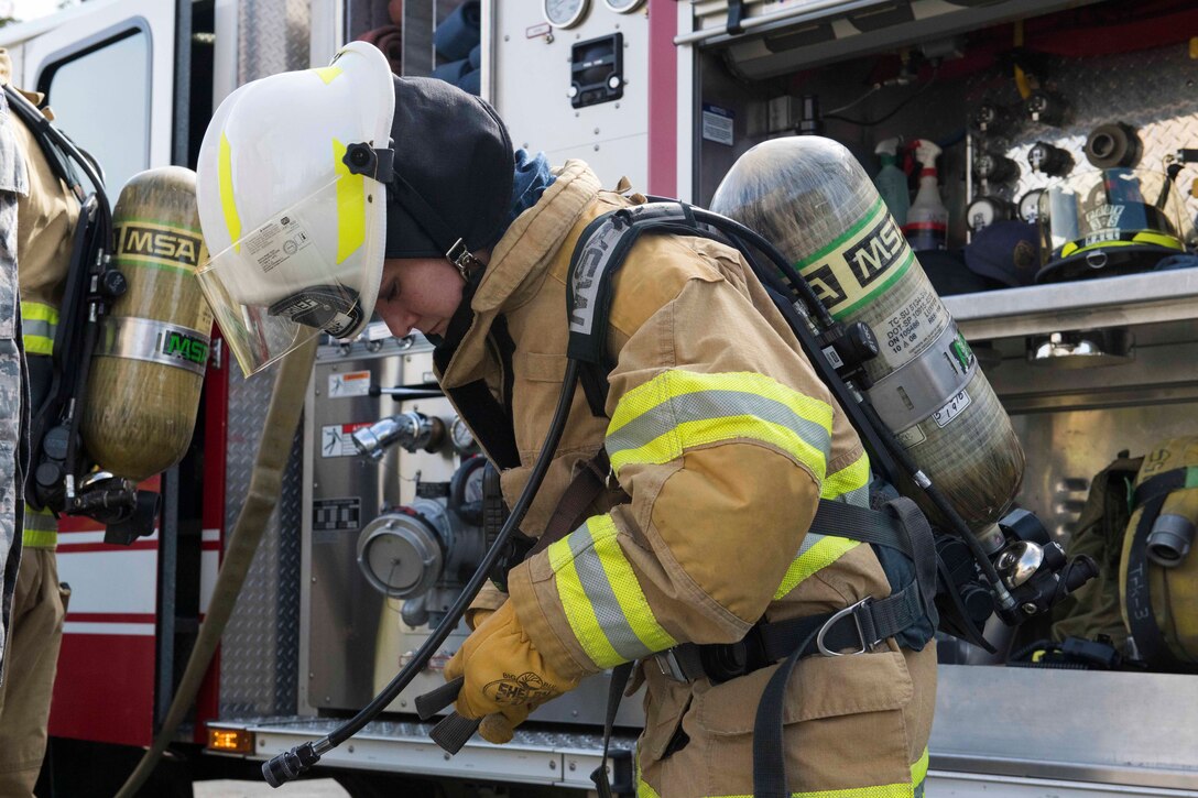 An airman dons a fire suit and equipment.