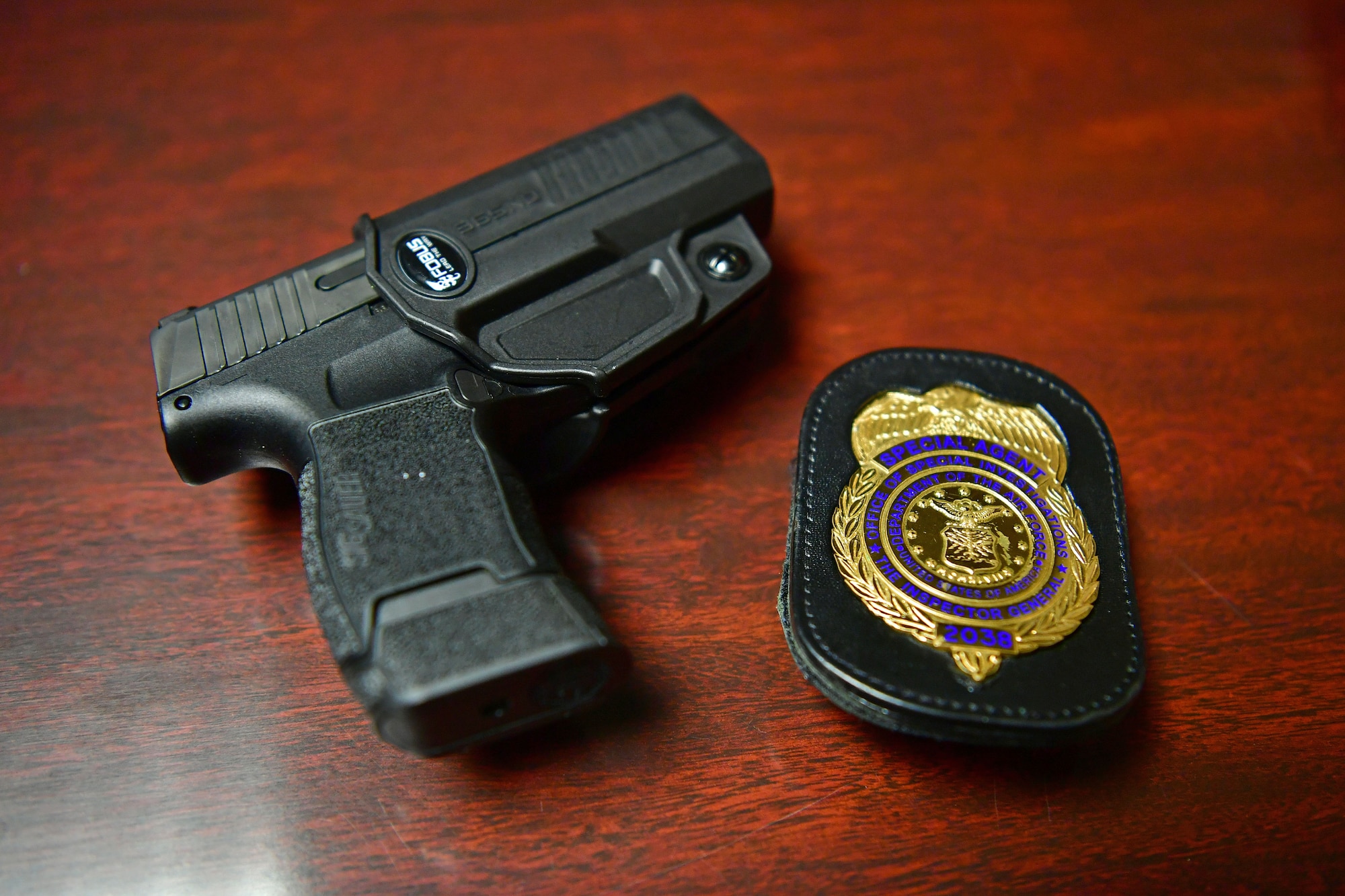 A photo of a pistol and an OSI badge on a table.