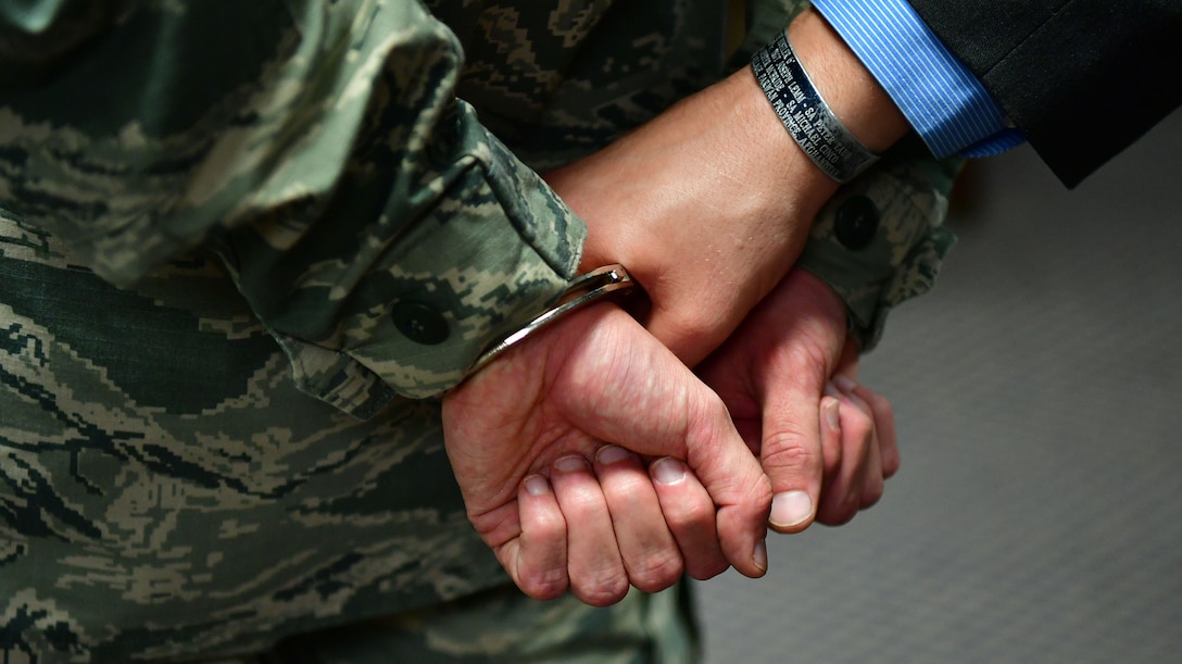 An Airman is put into handcuffs by a special agent.