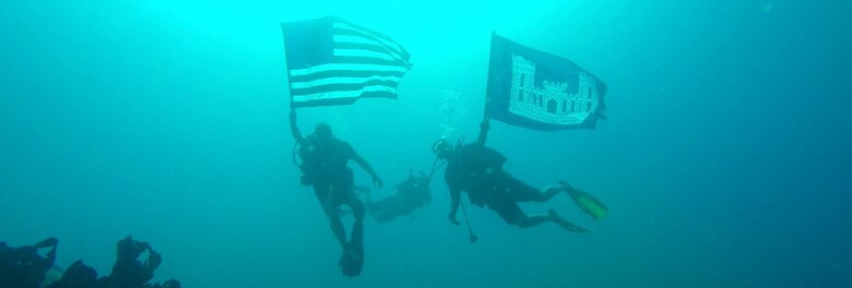 Rick Benoit (left) and Steve England (right) displayed the American and USACE colors after conducting above and below water inspections of waterfront infrastructure from Aug. 13-26 at the U.S. Army Garrison Kwajalein Atoll in the Republic of the Marshall Islands. Benoit and England serve on the the USACE Forward Response Technical Dive Team, which performs underwater inspections around the world on behalf of the Army’s Installation Management Command.