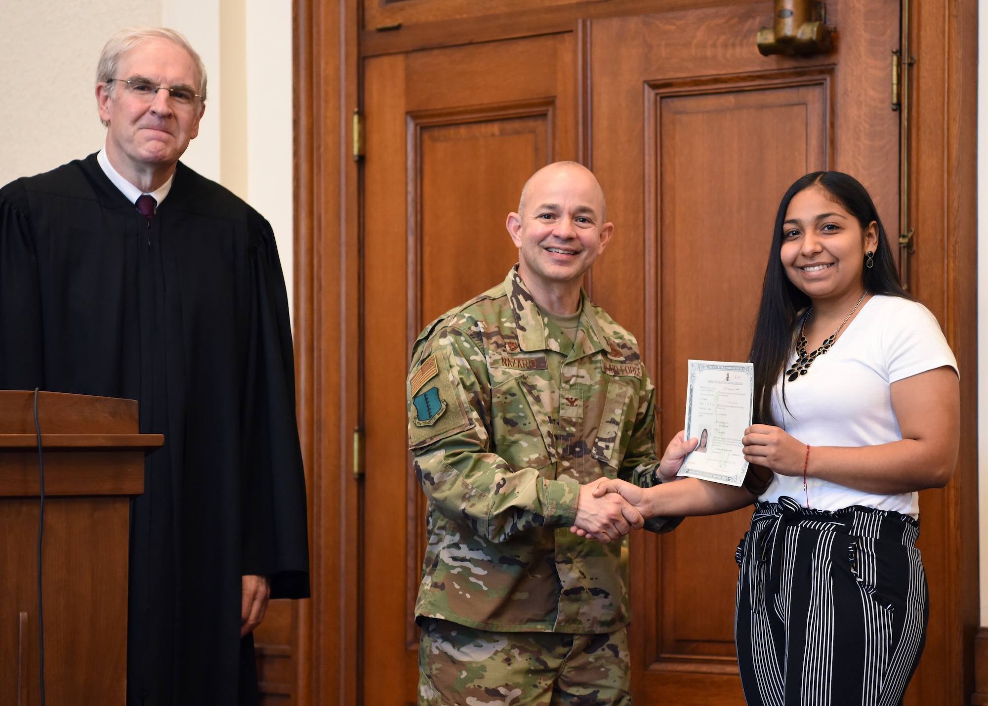 U.S. Air Force Col. Andres Nazario, 17th Training Wing commander presents a certificate to Ruth Sandate Garcia, a new U.S. citizen at the Naturalization Ceremony in the O.C. Fisher Federal Building September 4, 2019. Sandate Garcia was the youngest member of the group at 20 years old. (U.S. Air Force photo by Airman 1st Class Ethan Sherwood)