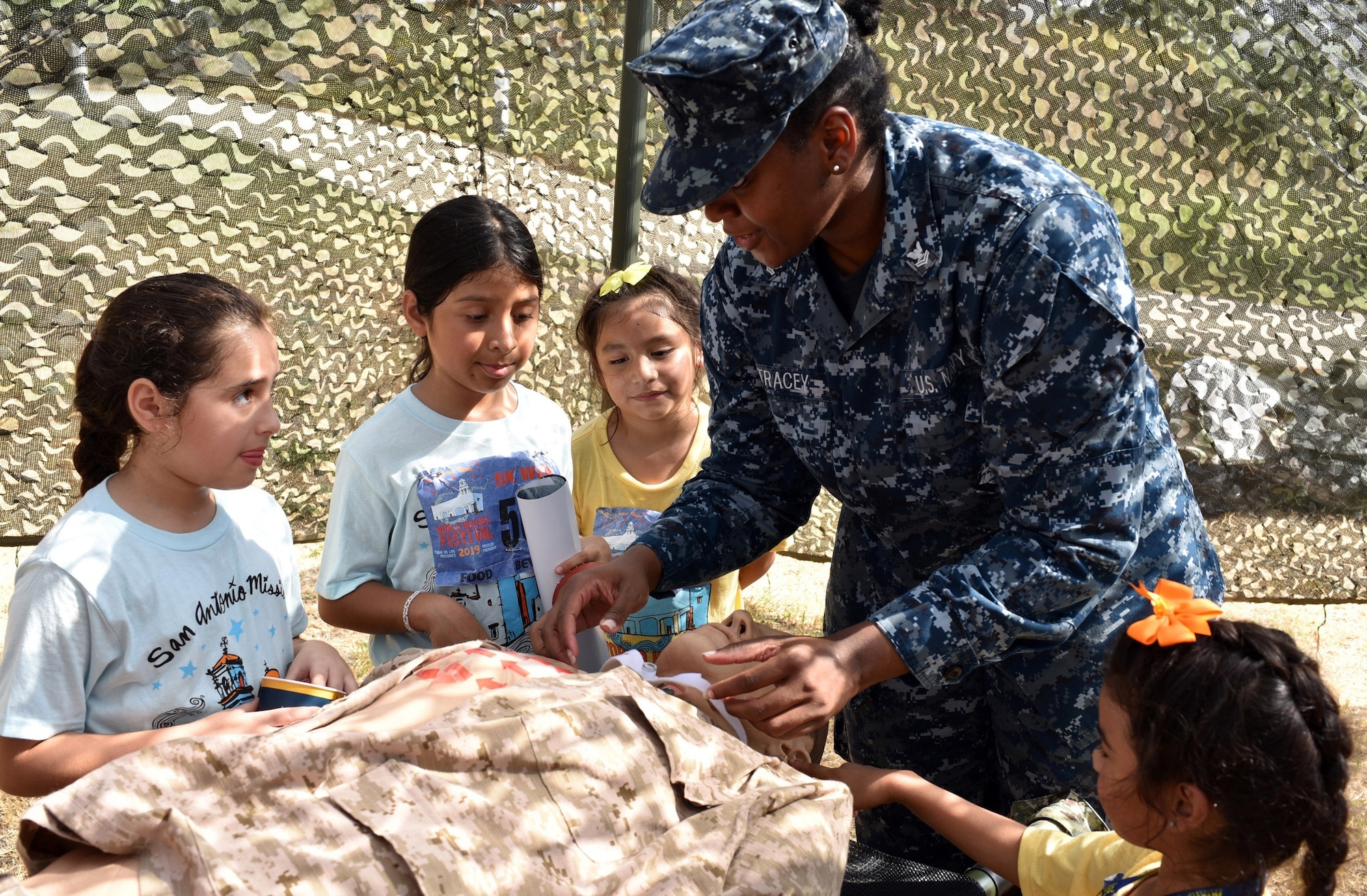 Petty Officer 2nd Class Jodi-Ann Tracey, an instructor assigned to Navy Medicine Education, Training and Logistics Command at Joint Base San Antonio-Fort Sam Houston, instructs young girls on the procedures to perform an emergency tracheotomy on a medical mannequin at Mission Pachanga during the annual World Heritage Festival held at Mission Park Pavilion Sept. 7. Mission Pachanga celebrated the city’s unique heritage and culture, past and present.