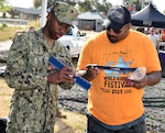 Petty Officer 2nd Class Mark Hambrick, assigned to Navy Recruiting District San Antonio, discusses the various rates of the Navy with an attendee of Mission Pachanga during the annual World Heritage Festival held at Mission Park Pavilion Sept. 7.