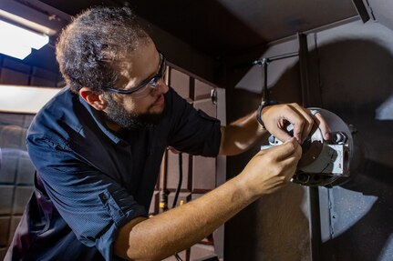 Code 930 Machinist Apprentice Tim Holland fits the actuator body component in the new Cold Spray booth at NNSY.