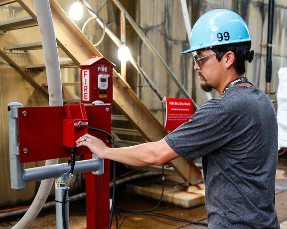 Christopher Blake from Norfolk Naval Shipyard's Temporary Services (Code 990) sounds the new fire alarm for testing.