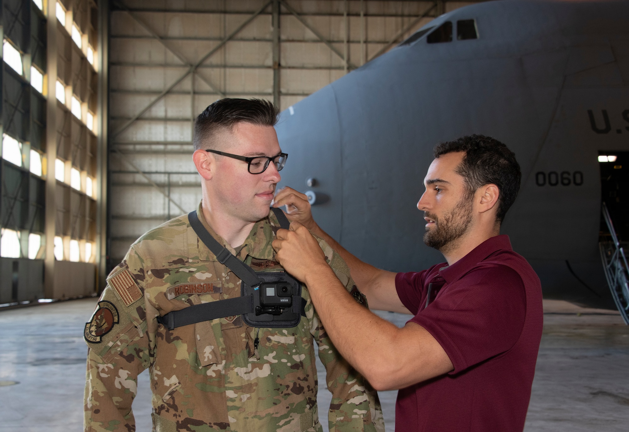 Joe Connolly, head of product for Sketchbox3D, adjusts the straps of a GoPro camera on U.S. Air Force Staff Sgt. Kevin Robinson, 22nd Airlift Squadron loadmaster evaluator Sept. 6, 2019, at Travis Air Force Base, California. The 22nd AS is partnering with Sketchbox3D to develop virtual reality training on C-5M Super Galaxy emergency escape slide egress procedures. (U.S. Air Force photo by Heide Couch)