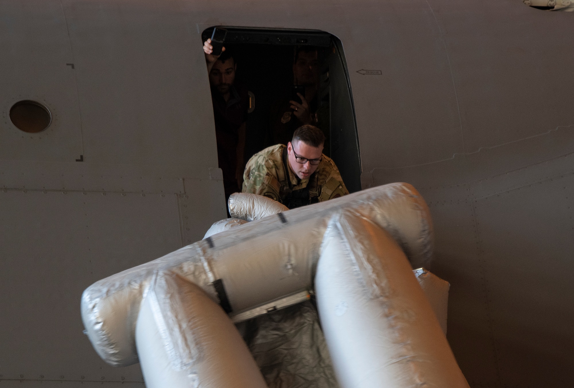 U.S. Air Force Staff Sgt. Kevin Robinson, 22nd Airlift Squadron loadmaster evaluator, deploys a C-5M Super Galaxy emergency escape slide Sept. 6, 2019, at Travis Air Force Base, California. Robinson wore a GoPro camera to record footage of the process to be used in development of a virtual reality training program on aircraft procedures. (U.S. Air Force photo by Heide Couch)