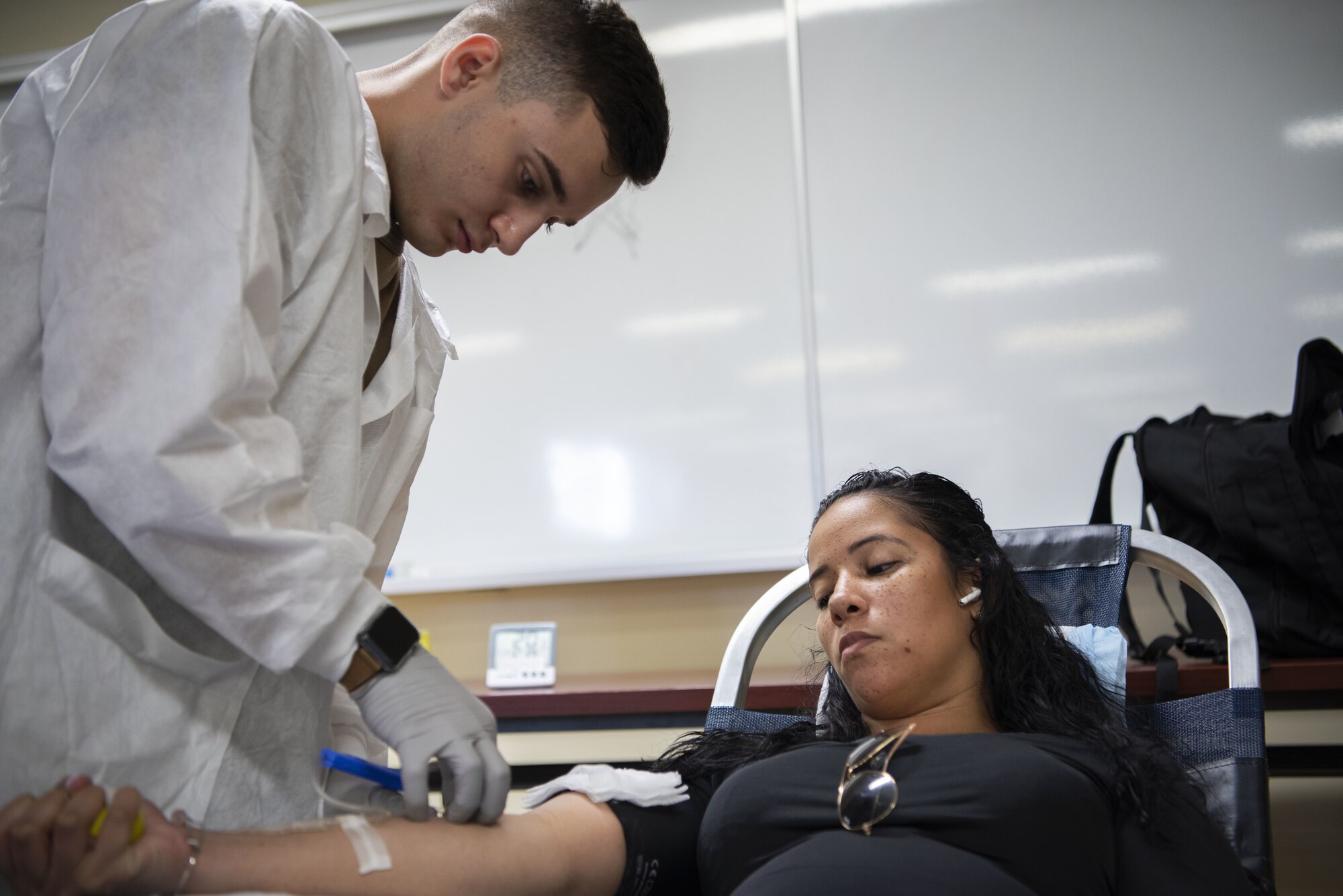 A man inserts a needle into a woman's arm.