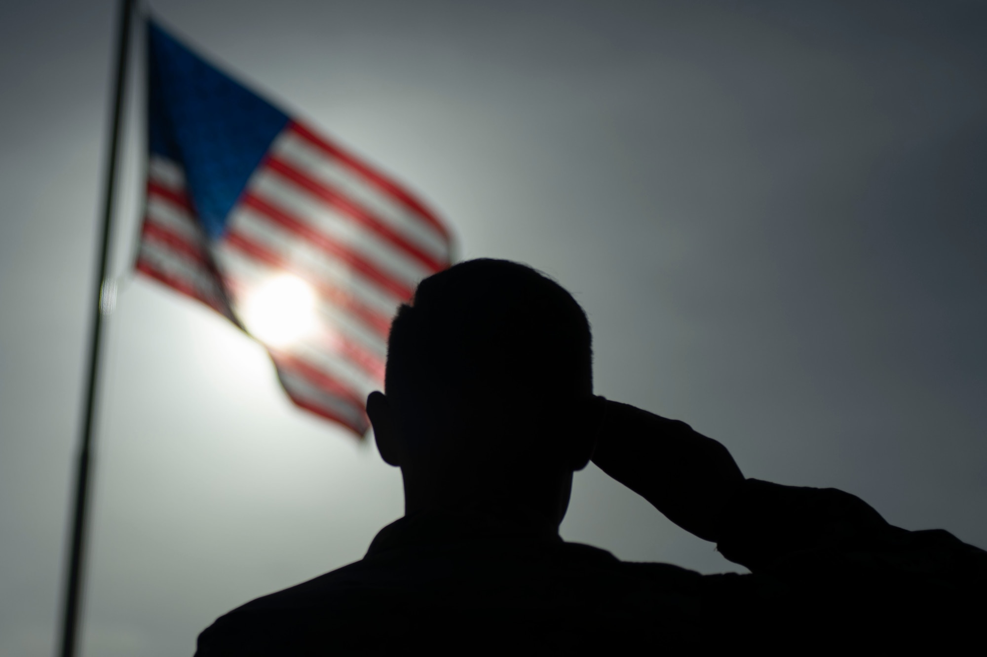 U.S. Air Force Staff Sgt. Devin Boyer, 435th Air Expeditionary Wing photojournalist, salutes the flag at Camp Simba, Kenya, Aug. 26, 2019. The 475th Expeditionary Air Base Squadron raised the flag for the first time since the base operating support-integrator mission started in 2017, signifying the change from tactical to enduring operations. (U.S. Air Force photo by Staff Sgt. Lexie West)
