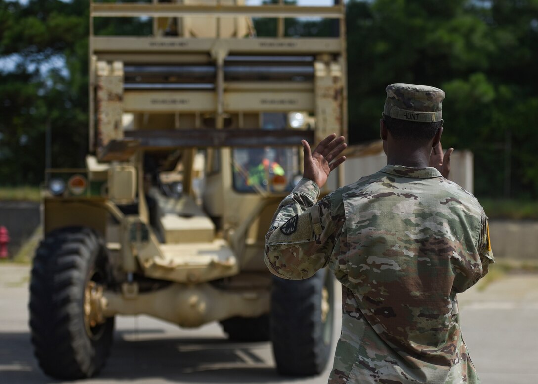 A U.S. Army Soldier guides a Port of Virginia dockworker during training for a cargo transportation exercise at Fort Story, Virginia, Aug. 20, 2019.