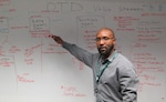 A man standing by a white board reviewing material written on it.