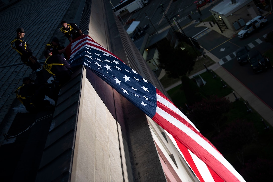 Works on the roof of the Pentagon unfurl a giant  American flag over a side of the building.