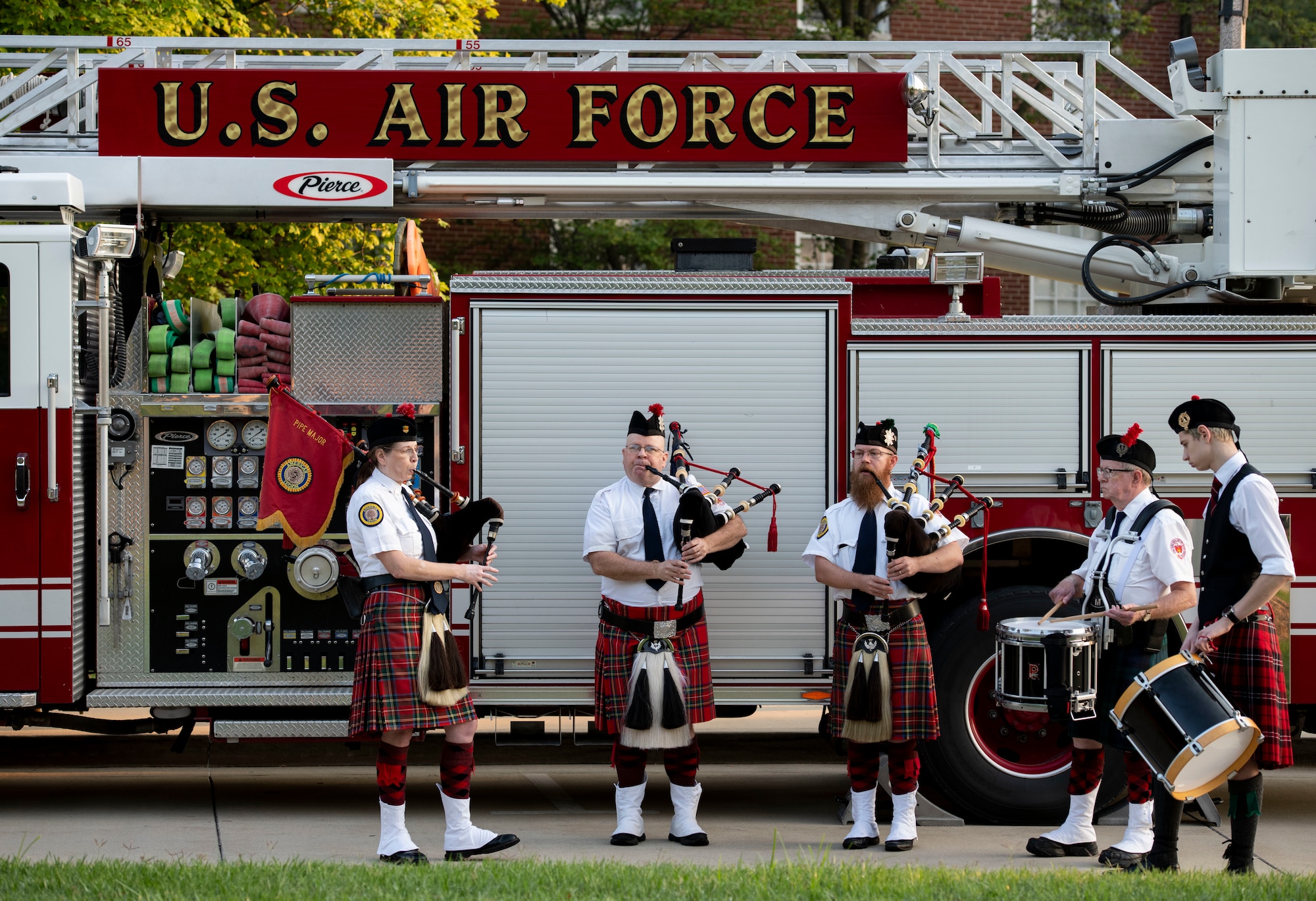 People play bagpipes in front of firetruck
