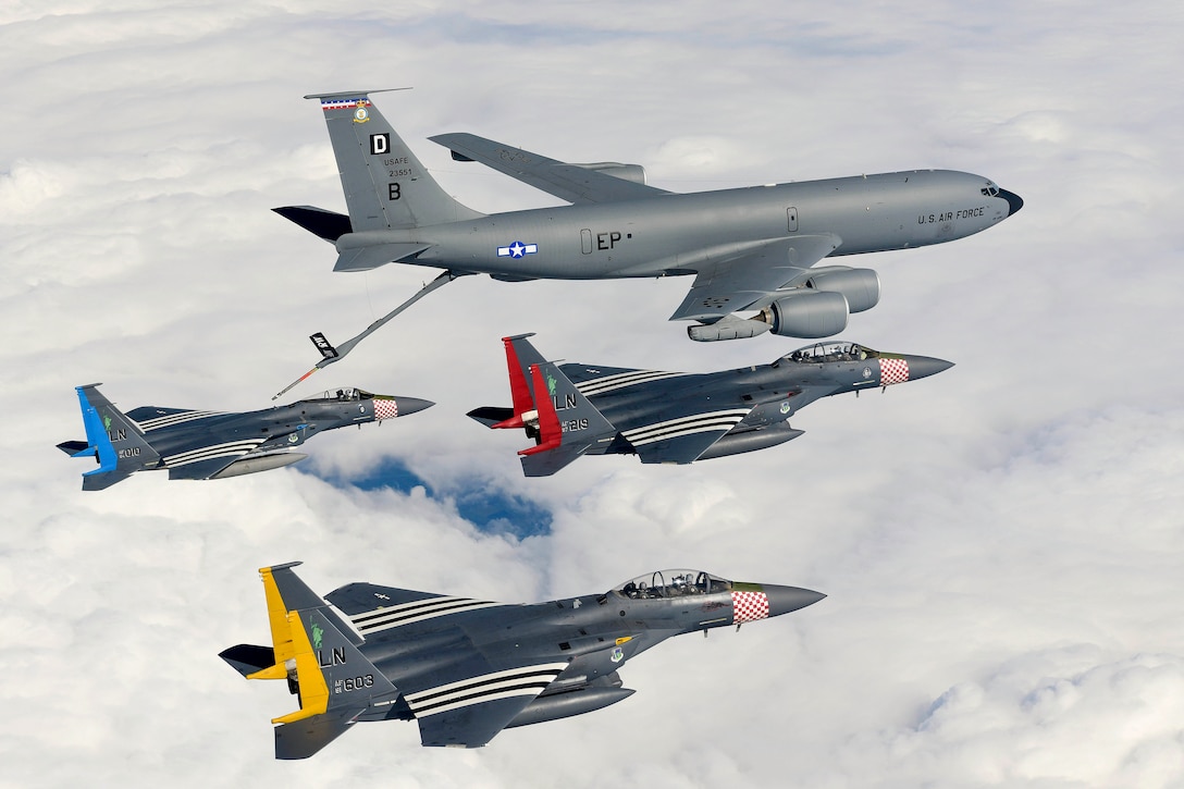 Four aircraft fly in formation through clouds.