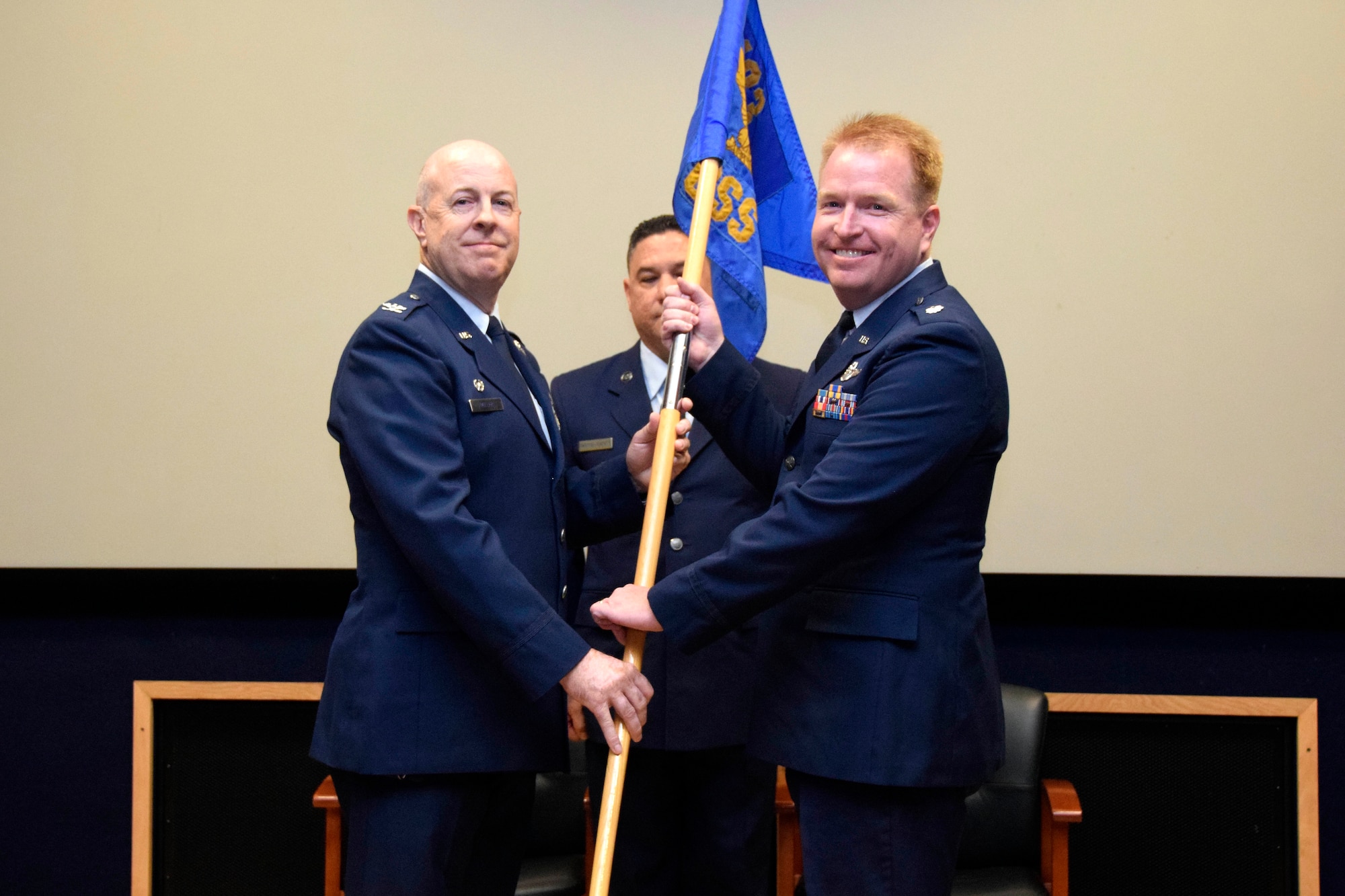 Lt. Col. Jonathan R. Behunin (right), accepts the guidon from Col. James C. “JC” Miller, 433rd Operations Group commander, during an assumption of command ceremony for the 433rd Operations Support Squadron at Joint Base San Antonio-Lackland, Texas, Sept. 7, 2019.