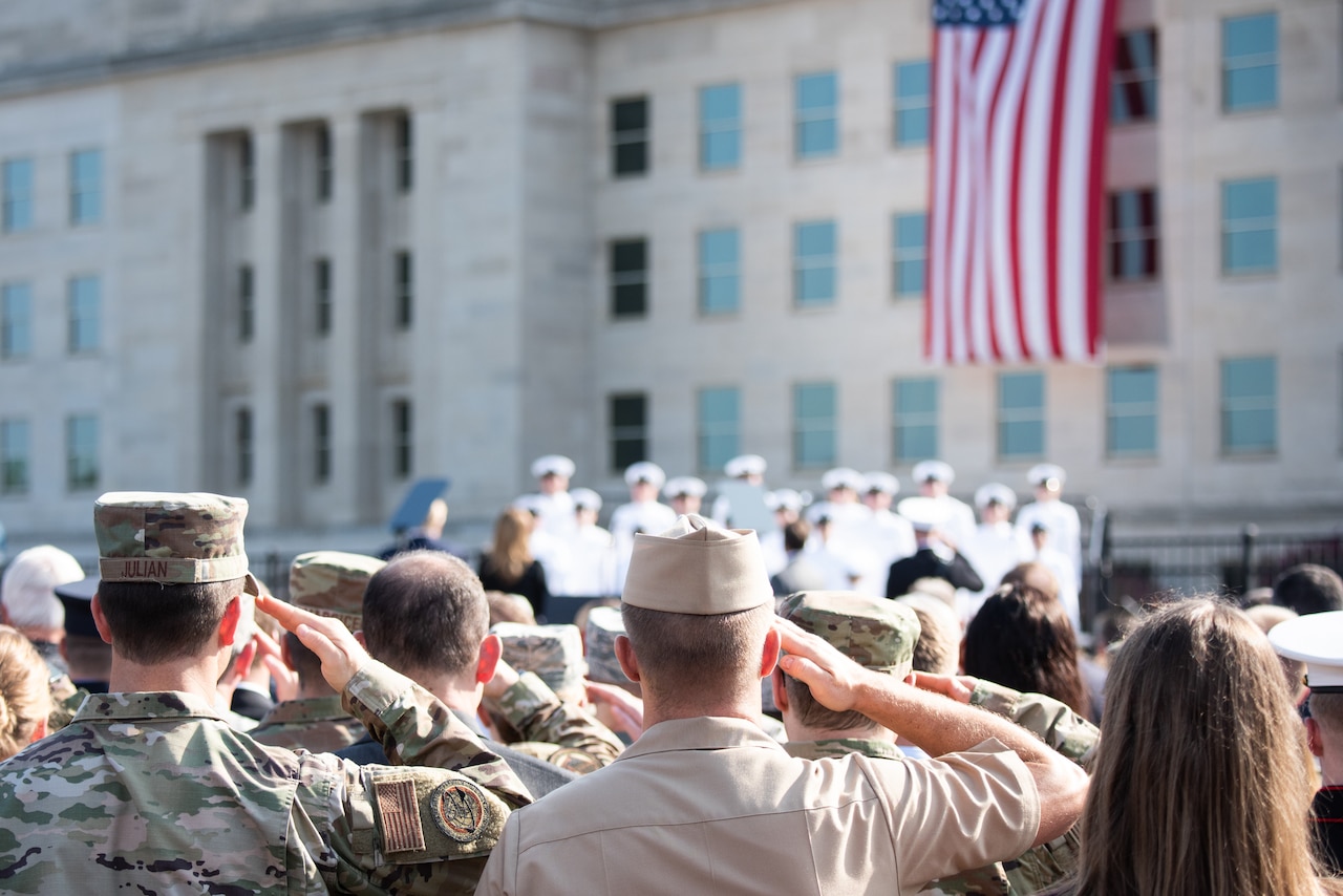 Service members salute toward a flag.