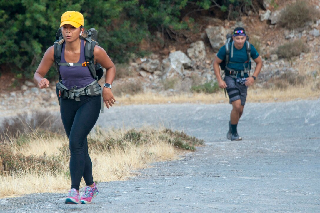 Hikers with backpacks walk on a trail.