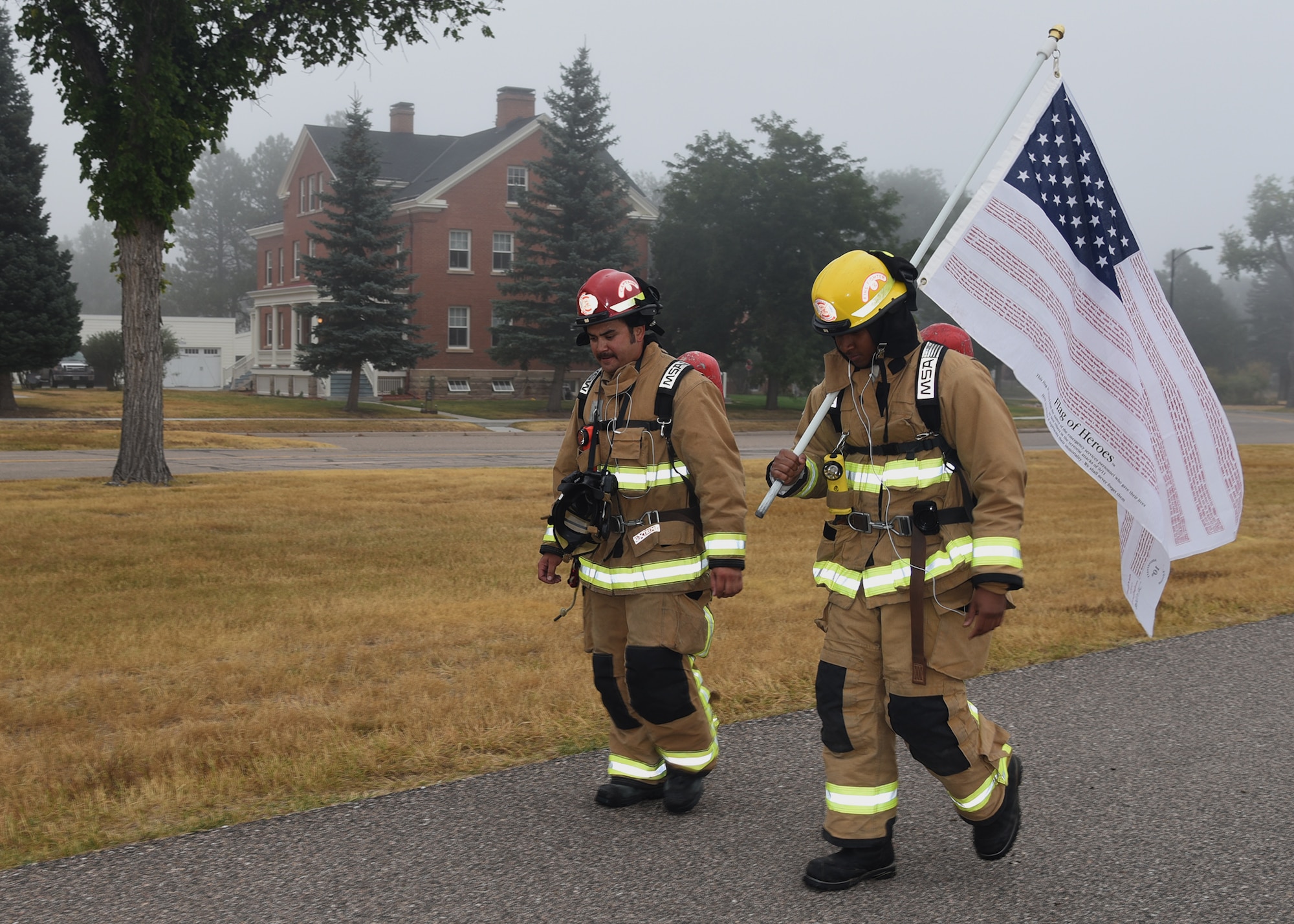 Senior Airman Ralph Mesidor and Cody Woolett, members of the Warren Fire Department, carry the Flag of Heroes around the base parade field Sept. 11 on F. E. Warren Air Force Base. Firefighters conducted the 24 hour vigil in firefighter gear honoring those who were killed in the attacks of Sept. 11, 2001.
