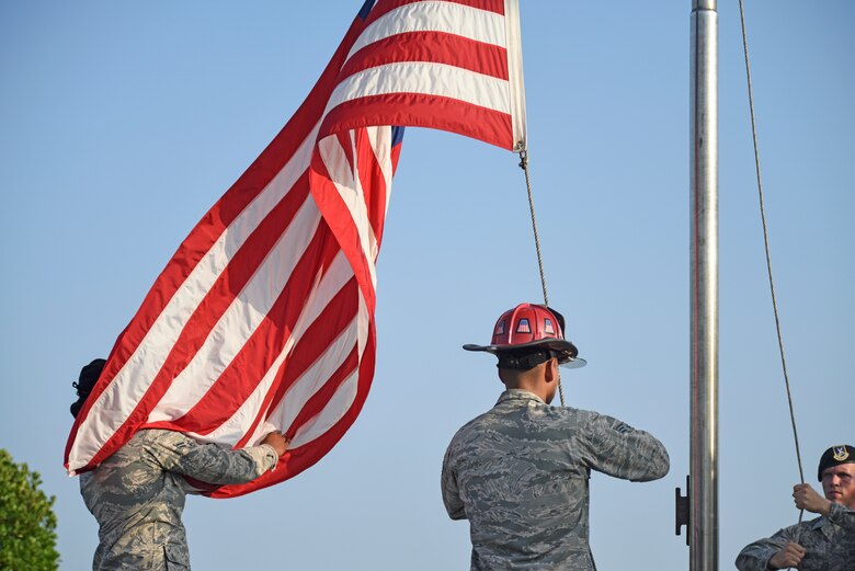 Members of the 8th Security Forces Squadron and 8th Civil Engineer Squadron lower the flag during the national anthem at the September 11 Remembrance ceremony at Kunsan Air Base, Republic of Korea, Sept. 11, 2019. The ceremony was held in remembrance of the 2,977 people who lost their lives on Sept. 11, 2001, in New York City, Washington, D.C., and outside Shanksville, Pennsylvania. The ceremony included a ringing of a bell, F-16 Fighting Falcon flyover and flag folding and presentation. (U.S. Air Force photo by Staff Sgt. Mackenzie Mendez)