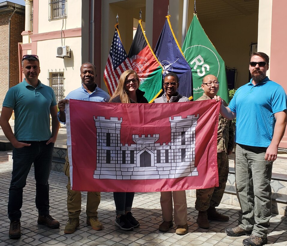 Members of the USACE Power Team and construction team display the flag symbol of the “Castle Strong” mission each is enduring.