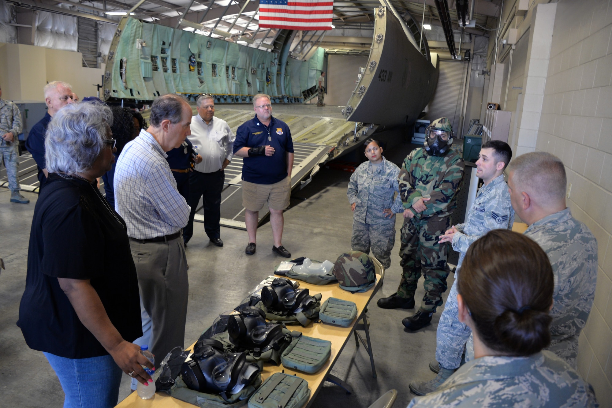 Senior Airman Taylor D. Mogford, 433rd Logistics Readiness Squadron(right), talks to honorary commanders about the proper donning and wear of the joint service lightweight integrated suit technology, a chemical weapon protection suit, during a tour of the 433rd Mission Support Group at Joint Base San Antonio-Lackland, Texas Sept. 7, 2019.