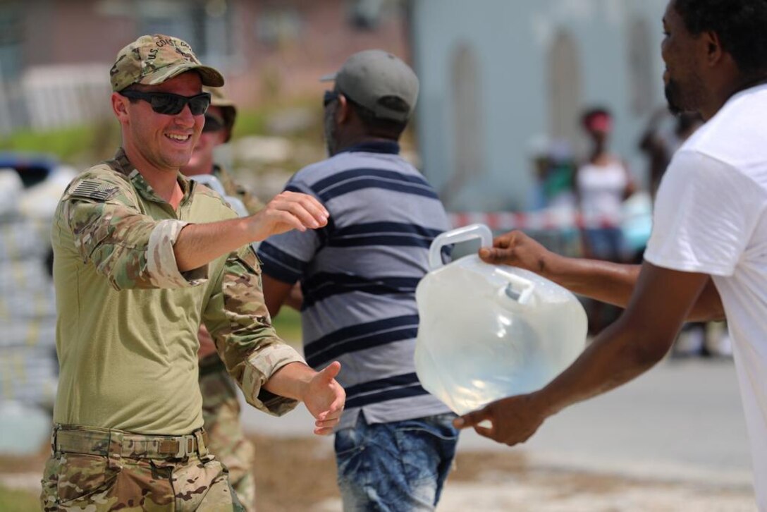 A U.S. Coast Guardsman provides water to those affected by Hurricane Dorian in the Bahamas, Sept. 8, 2019.  DLA Troop Support provided more than 1,400 cases of bottled water to various Department of Defense customers in support of the hurricane relief efforts. (U.S. Coast Guard Courtesy Photo)