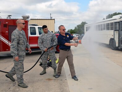 Steve Young, VIA Metropolitan Transit vice president of information technology, experiences discharging a fire hose during a tour of the 433rd Mission Support Group at Joint Base San Antonio-Lackland Sept. 7. Young is paired with Lt. Col. Travis J. Hatley, 74th Aerial Port Squadron commander.