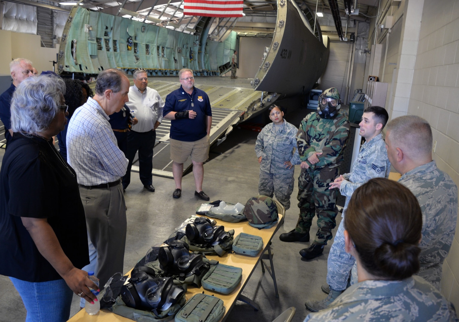 Senior Airman Taylor D. Mogford, 433rd Logistics Readiness Squadron (right), talks to honorary commanders about the proper donning and wear of the joint service lightweight integrated suit technology, a chemical weapon protection suit, during a tour of the 433rd Mission Support Group at Joint Base San Antonio-Lackland Sept. 7.