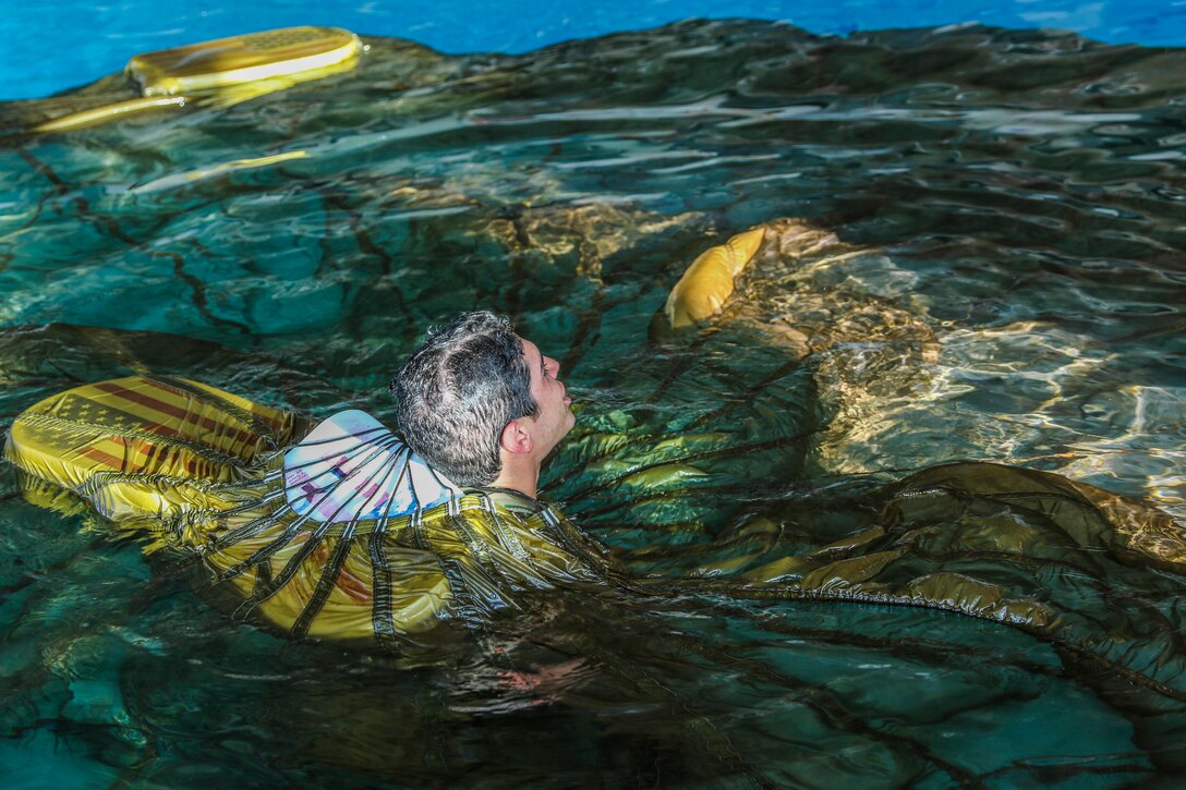 A soldier swims with a parachute around him.