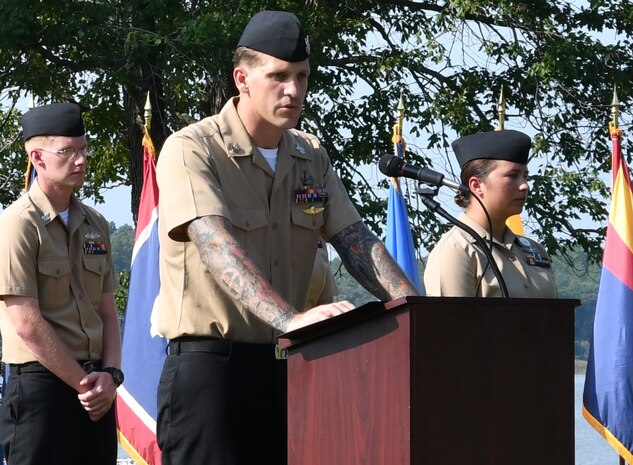 IMAGE: DAHLGREN. Va. (Sept. 11, 2019) – Navy chief select Cody Wilcoxson shares a story of heroism in response to the terrorist attacks and ensuing tragedies on 9/11. Wilcoxson was one of seven chief select ‘heroism readers’ based at commands located on Naval Surface Facility Dahlgren who recounted acts of heroism on that tragic day in our nation’s history.

Wilcoxson – reading to military, first responders, government and contractor personnel gathered to honor the victims of 9/11 – recounted that:
“Jason Thomas and Dave Karnes, two former U.S. Marines, put their uniforms back on and searched through rubble that could have collapsed at any moment. Once both Marines reached the collapsed towers — the site now covered in ash and debris — they began searching for survivors, but first, they found each other. Along with other first responders, the pair climbed over the dangerous field of metal, concrete, and dust, calling out, ‘United States Marines! If you can hear us, yell or tap!’ They found two survivors.”