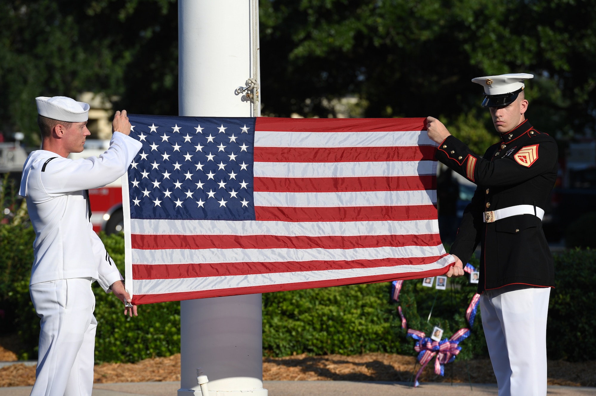 U.S. Navy Aerographers Mate 1st Class Daniel Ealy, Center for Naval Aviation Technical Training Unit Keesler instructor, and U.S. Marine Staff Sgt. Jacob Nixon, Keesler Marine Detachment curriculum manager, display the U.S. flag during a 9/11 memorial ceremony hosted by CNATTU Keesler in front of the 81st Training Wing headquarters building on Keesler Air Force Base, Mississippi, Sept. 11, 2019. The event honored those who lost their lives during the 9/11 attacks. (U.S. Air Force photo by Kemberly Groue)