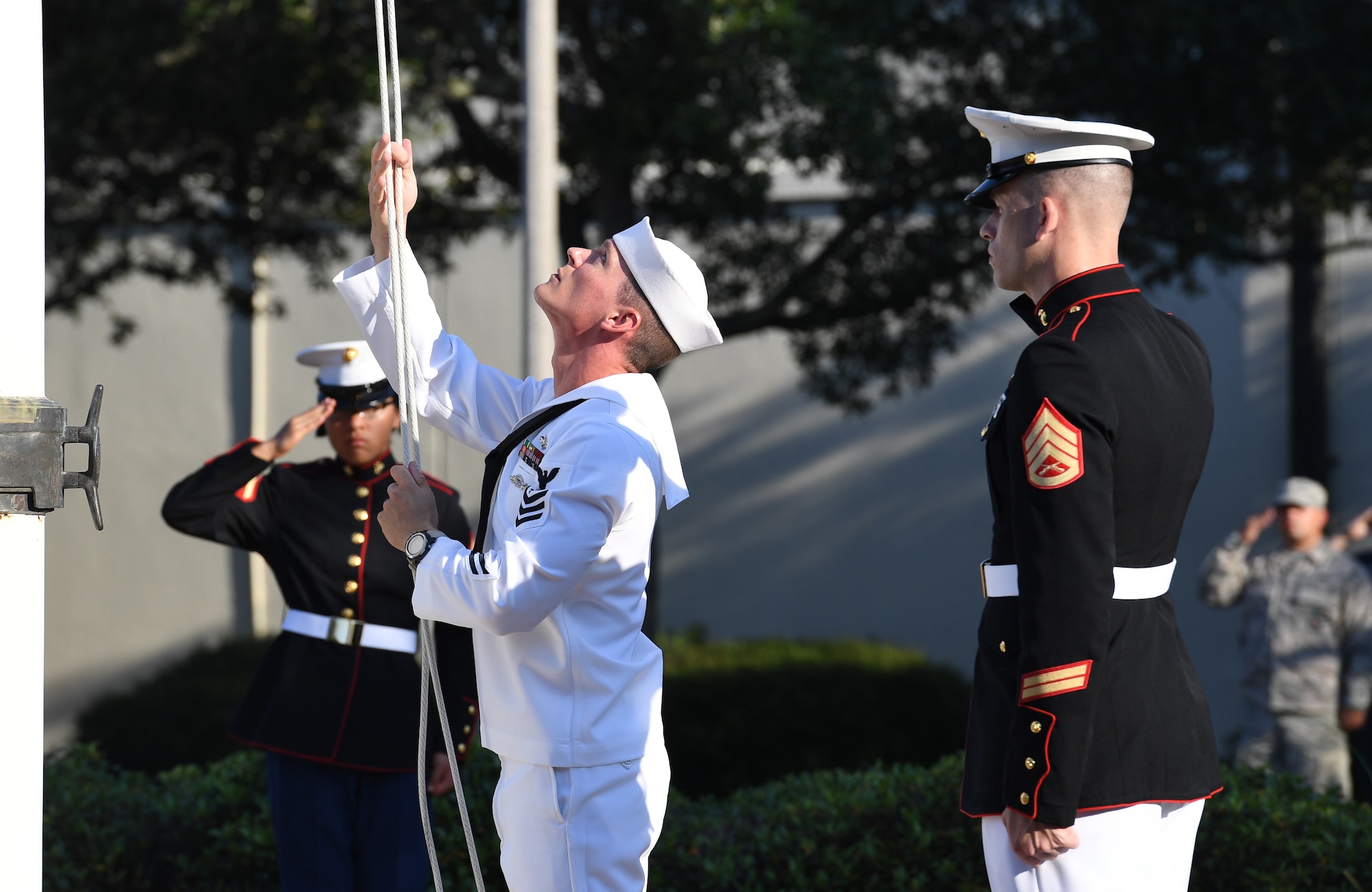 U.S. Navy Aerographers Mate 1st Class Daniel Ealy, Center for Naval Aviation Technical Training Unit Keesler instructor, raises the U.S. flag as U.S. Marine Staff Sgt. Jacob Nixon, Keesler Marine Detachment curriculum manager, renders a salute during a 9/11 memorial ceremony hosted by CNATTU Keesler in front of the 81st Training Wing headquarters building on Keesler Air Force Base, Mississippi, Sept. 11, 2019. The event honored those who lost their lives during the 9/11 attacks. (U.S. Air Force photo by Kemberly Groue)