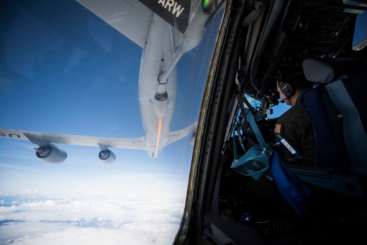 An Air Force pilot watches as his plane approaches another military aircraft.