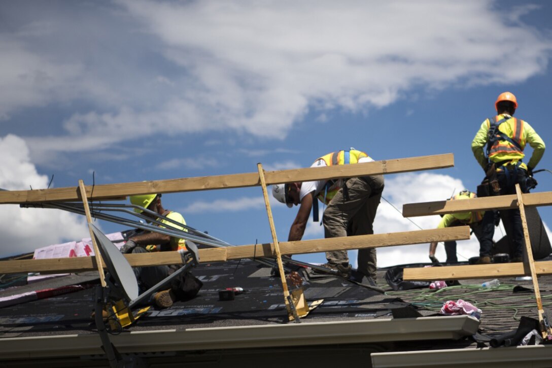 Workers on roof of military housing.