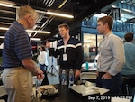 Bryan Kessel (right) and Nathan Desloover (center), both engineers at Naval Surface Warfare Center, Carderock Division, speak with Rear Adm. Lorin Selby, chief engineer and deputy commander for Ship Design, Integration and naval Engineering at NAVSEA, during the Hack the Machine 2019 in New York City on Sept. 7, 2019. (U.S. Navy photo by Garry Shields/Released)