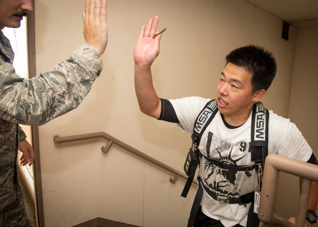 A firefighter from the local community exchanges a high-five with a volunteer from the 374th Civil Engineer Squadron fire and emergency services flight upon finishing the ascent of the 9th floors, during a 9/11 Tower Run, Sept. 11, 2019, at Yokota Air Base, Japan.
