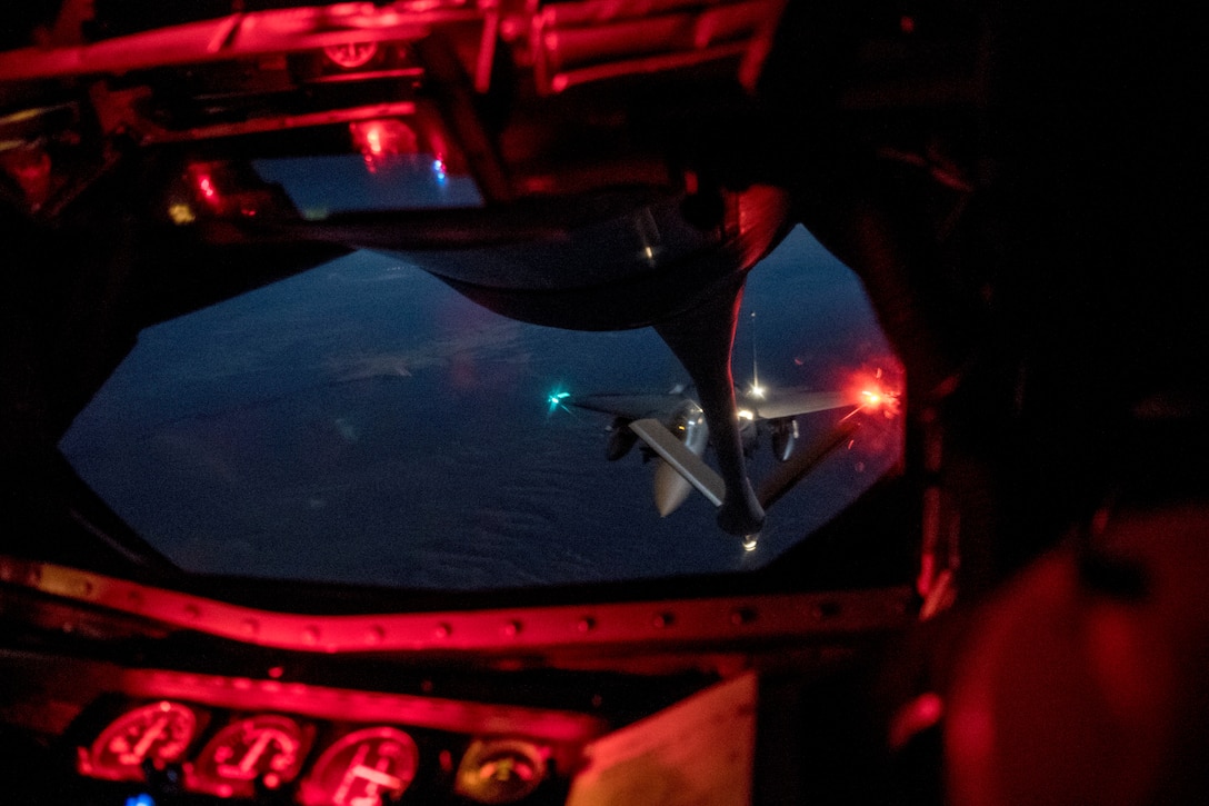 A military jet prepares for an aerial refueling at night.