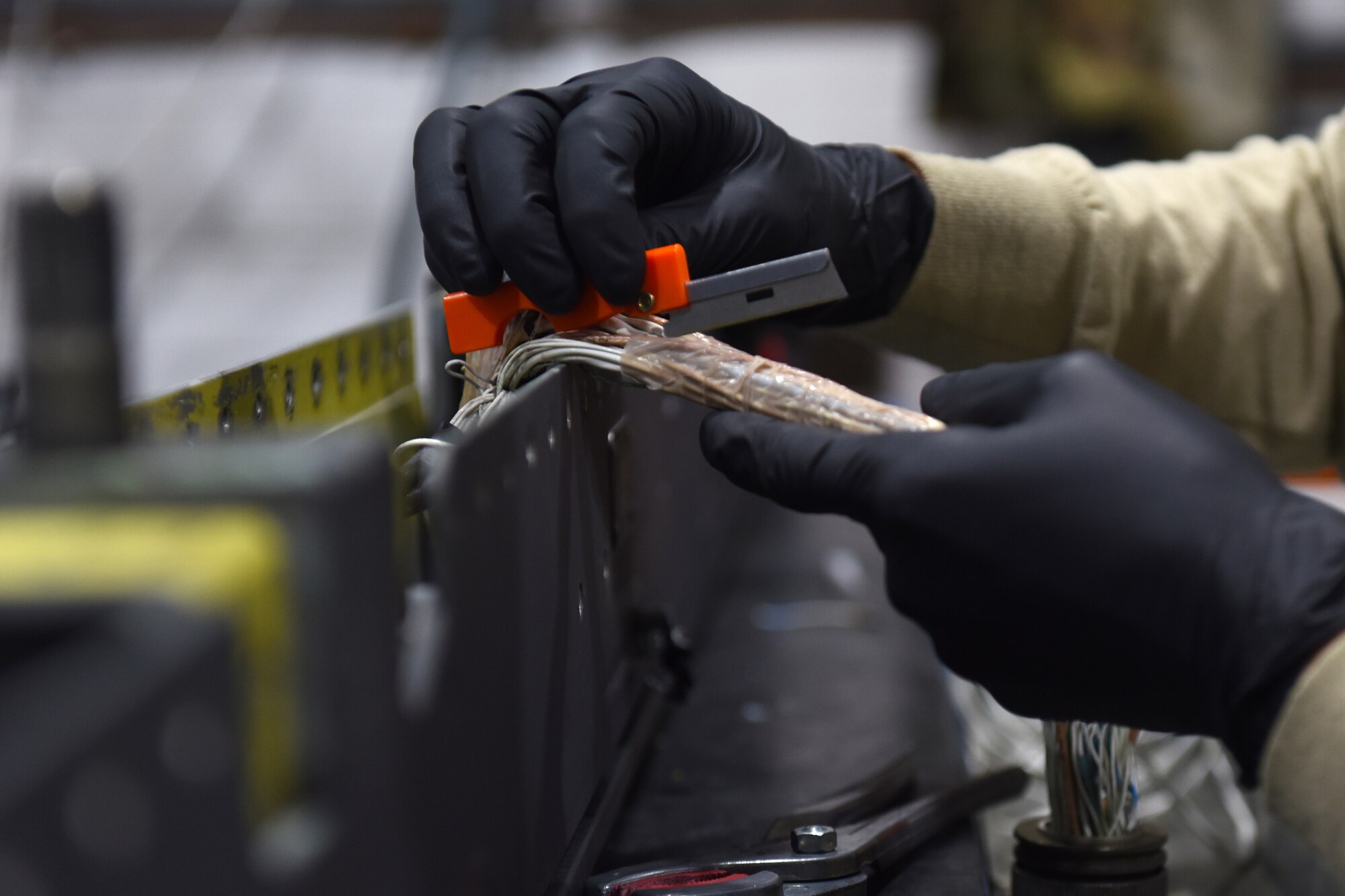 An armament maintenance technician from the 48th Munitions Squadron cuts plastic wiring cover from a pylon at Royal Air Force Lakenheath, England, Sept. 11, 2019. The Armament flight works on all weapons-related equipment from both the 48th Fighter Wing F-15C Eagle and F-15E Strike Eagles. (U.S. Air Force photo by Airman 1st Class Madeline Herzog)