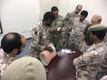 A New Jersey Army National Guard Soldier discusses a Tactical Combat Casualty Care (TCCC) scenario with members of the Qatari Emiri Land Forces (QELF) Sept. 8 -12, 2019, at the Qatar Emiri Land Force Artillery School in Al Rayyan Municipality, Qatar.