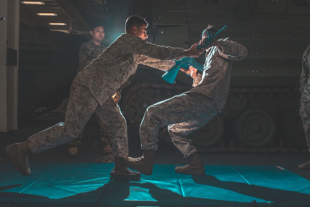 Two Marines practice martial arts in a dark room.