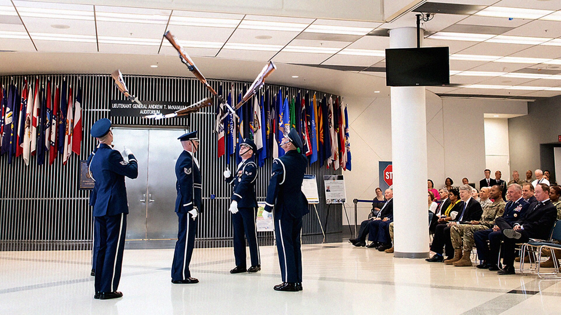 Members of the Air Force Honor Guard Drill Team toss bayonets during their performance as audience watches.