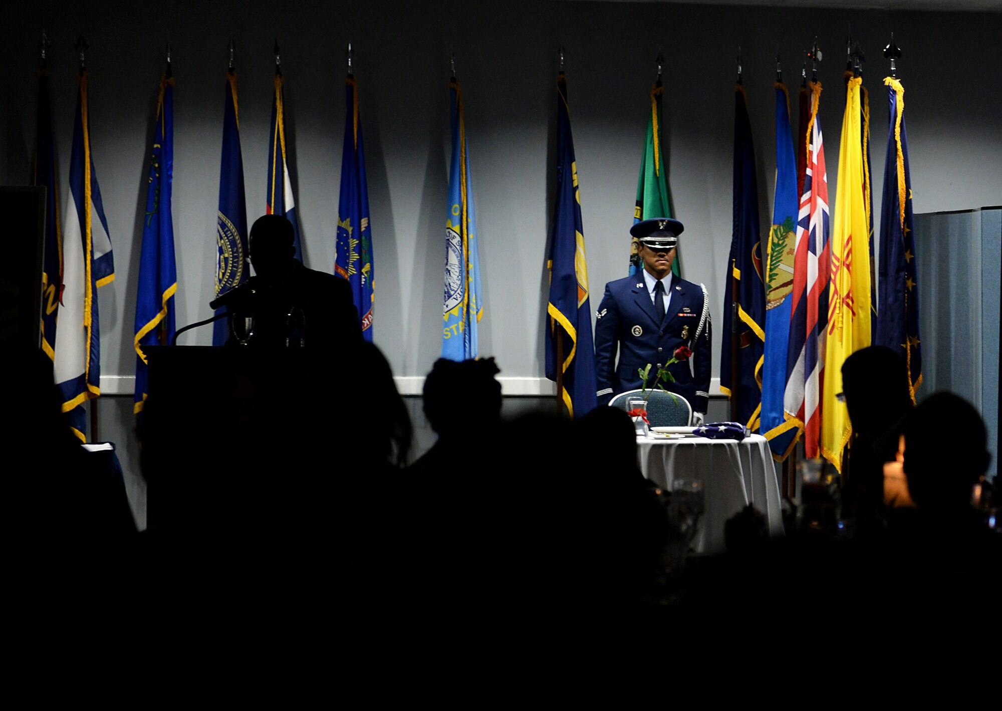 A Columbus Air Force Base Honor Guardsman stands before the POW/MIA table during a presentation at the Senior NCO Induction Ceremony Sept. 9, 2019, at the Club on Columbus AFB, Miss. The table is set in honor and remembrance of those who have fallen or became prisoners of war in the line of action. (U.S. Air Force photo by Airman 1st Class Hannah Bean)
